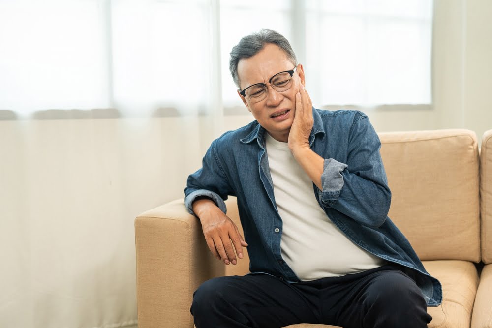 Old man senior puts his hand on his mouth and feels toothache - Dental Emergency in Georgina, ON